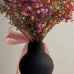 Romantic Updo - A black vase with flowers in it on a table