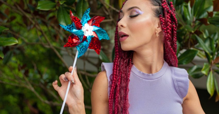 Extensions - Model with Braided Hair in a Lavender Blouse Blowing on a Pinwheel