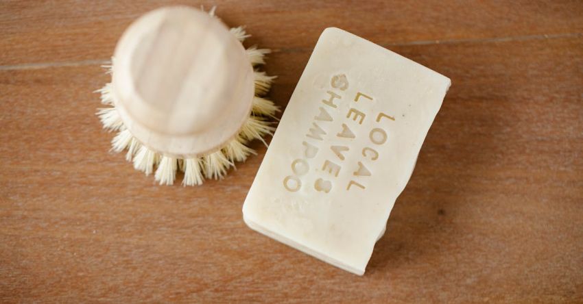 Dry Shampoo - Top view of zero waste beauty brush and dry shampoo with inscription on brown background