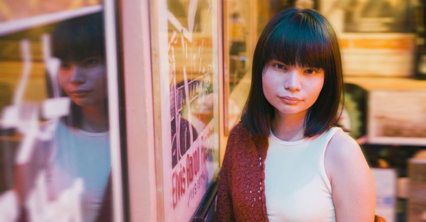 Fringe Haircut - A woman in a red sweater and white jacket standing in front of a store